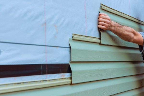 Installation of vinyl siding plastic panels on facade wall new home by an contractor